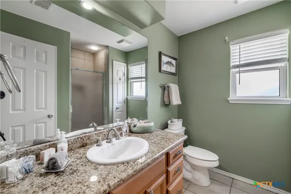 a bathroom with a granite countertop sink toilet and mirror