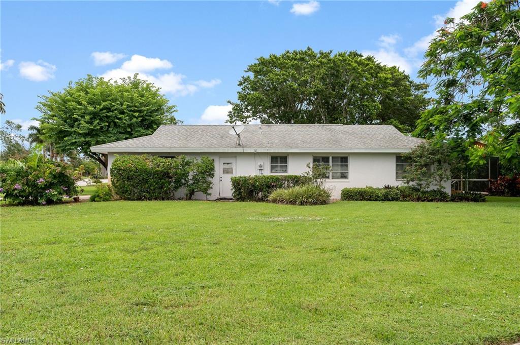 59 Pebble Beach Boulevard Naples, FL 34113 - Photo 3 of 32 a front view of a house with a garden