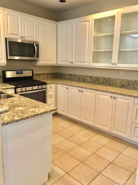 5 Torrigiani Aisle Irvine, CA 92606 - Photo 8 of 28 a kitchen with granite countertop white cabinets stainless steel appliances and a sink