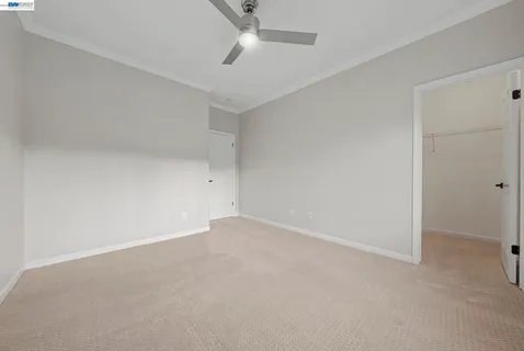 an empty room with a ceiling fan and carpet