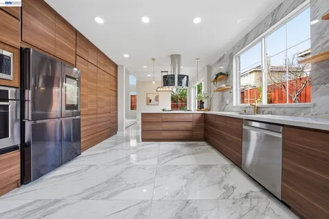 a kitchen with stainless steel appliances kitchen island granite countertop a refrigerator and a sink