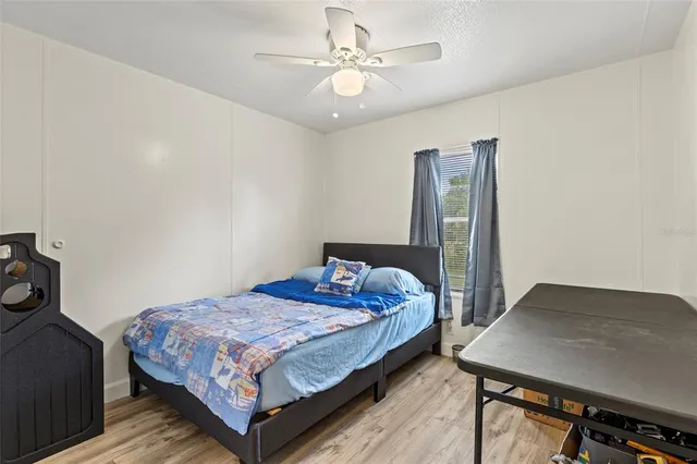 a bedroom with a bed a dresser and potted plant