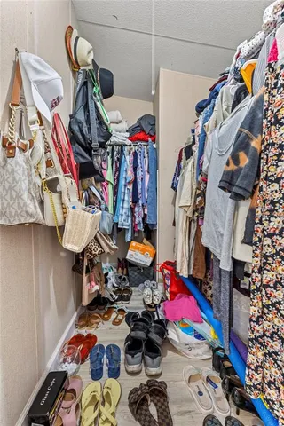 a view of walk in closet with clothes and shoes