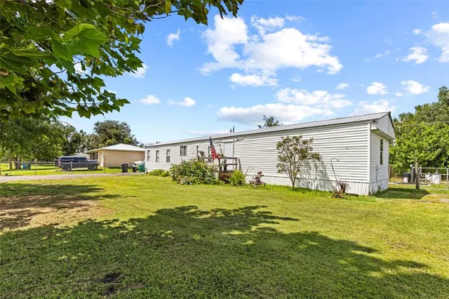 a view of a house with a big yard and a large tree