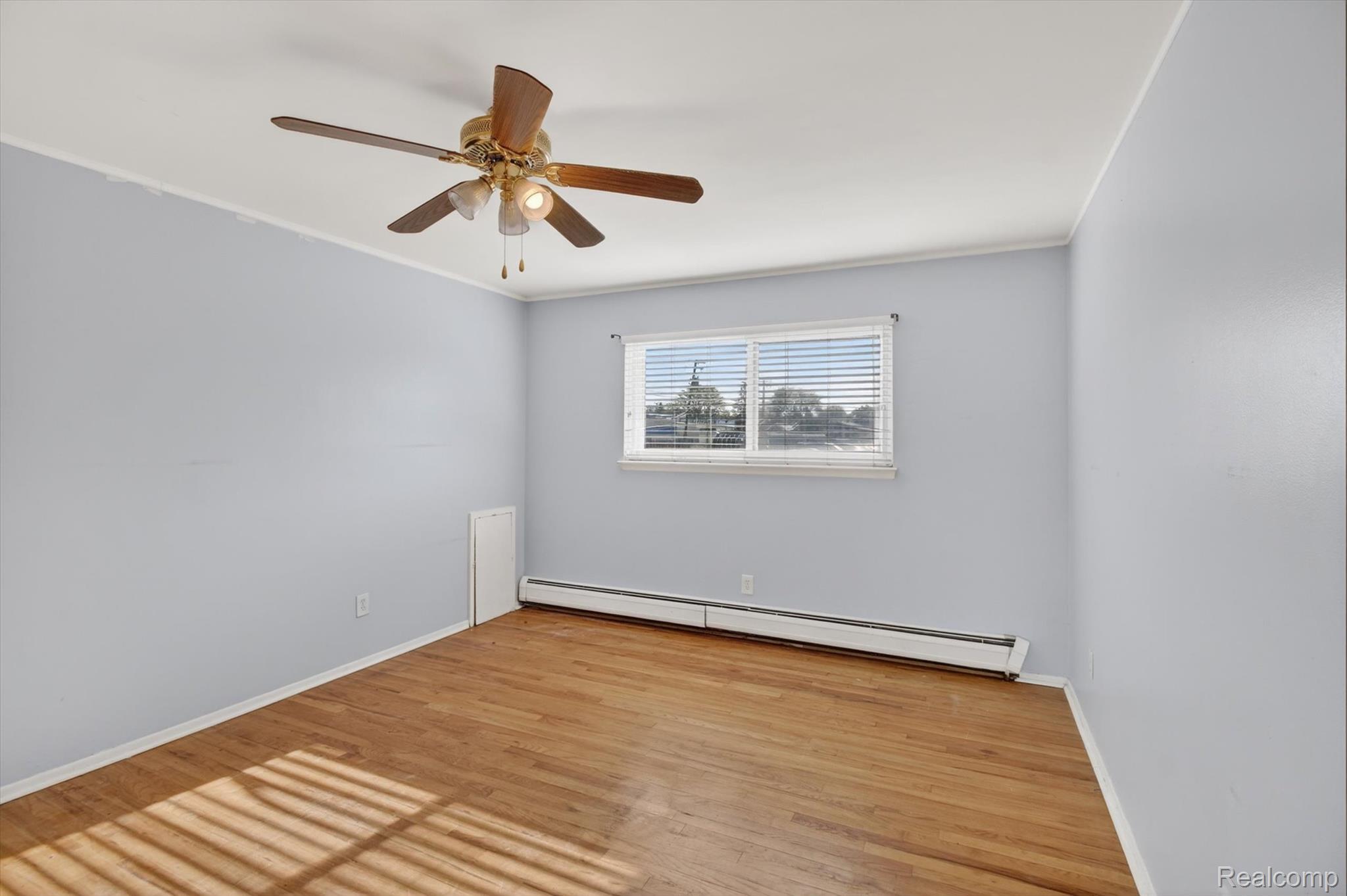 25301 Five Mile Road, Unit 109 Redford, MI 48239 - Photo 20 of 22 Unfurnished room featuring baseboard heating, light wood-type flooring, a ceiling fan, and crown molding