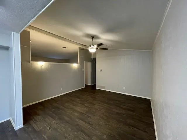 an empty room with wooden floor closet and fan