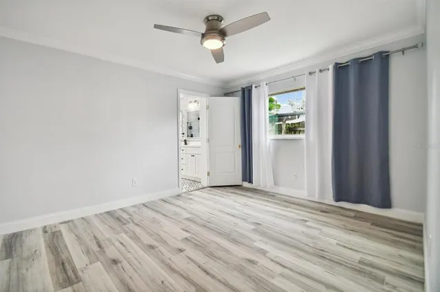 a view of empty room with wooden floor and fan