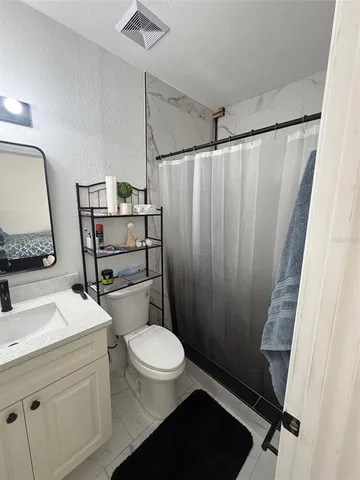 a bathroom with a sink a toilet a mirror and shower curtain