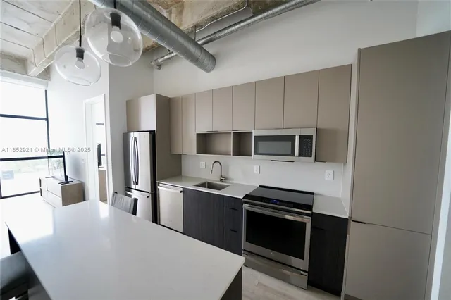 a kitchen with stainless steel appliances a refrigerator a stove a sink and white cabinets