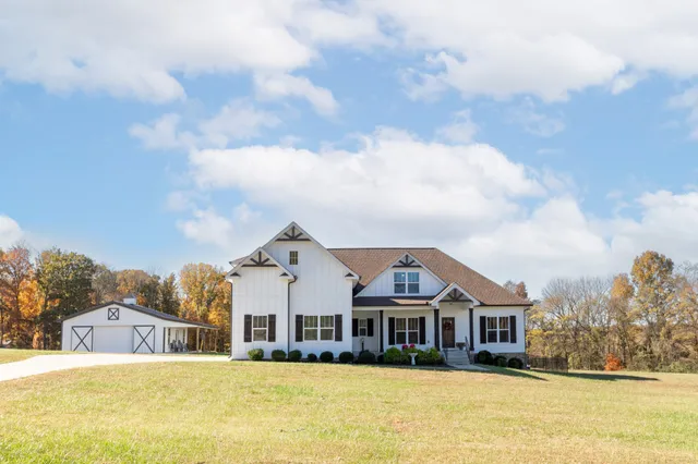 a view of a house with a big yard and large trees