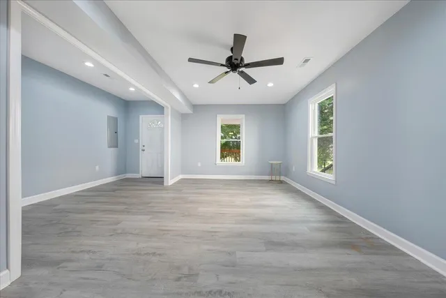 an empty room with windows and fan