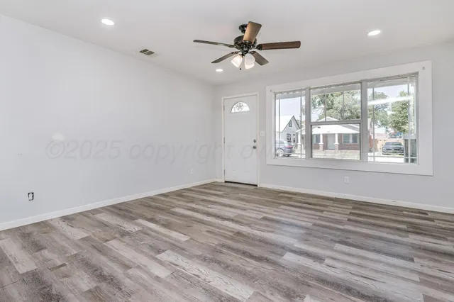 a view of empty room with wooden floor and fan