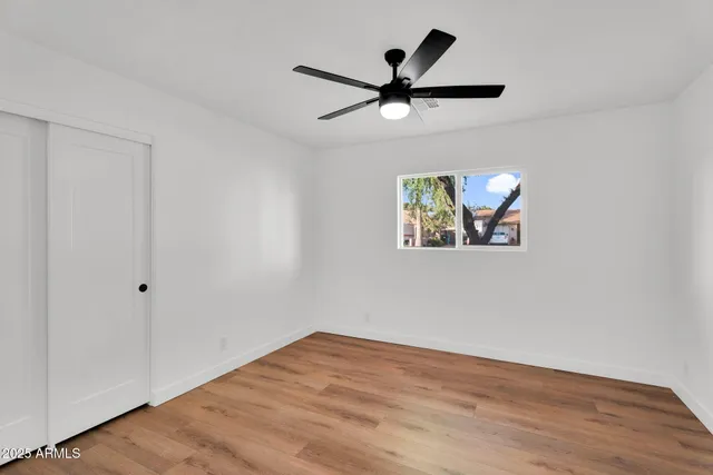 an empty room with wooden floor and ceiling fan