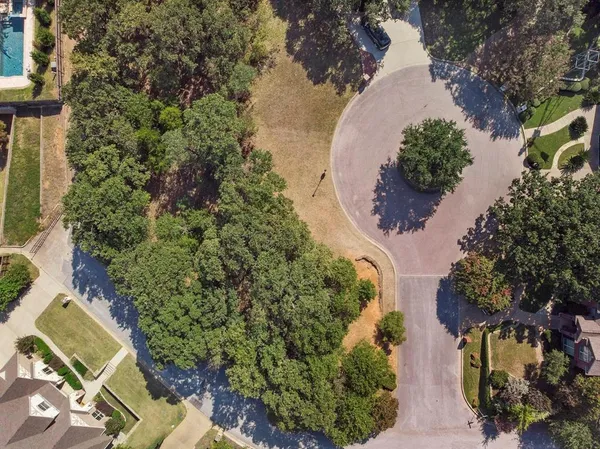 an aerial view of a house with outdoor space and trees all around