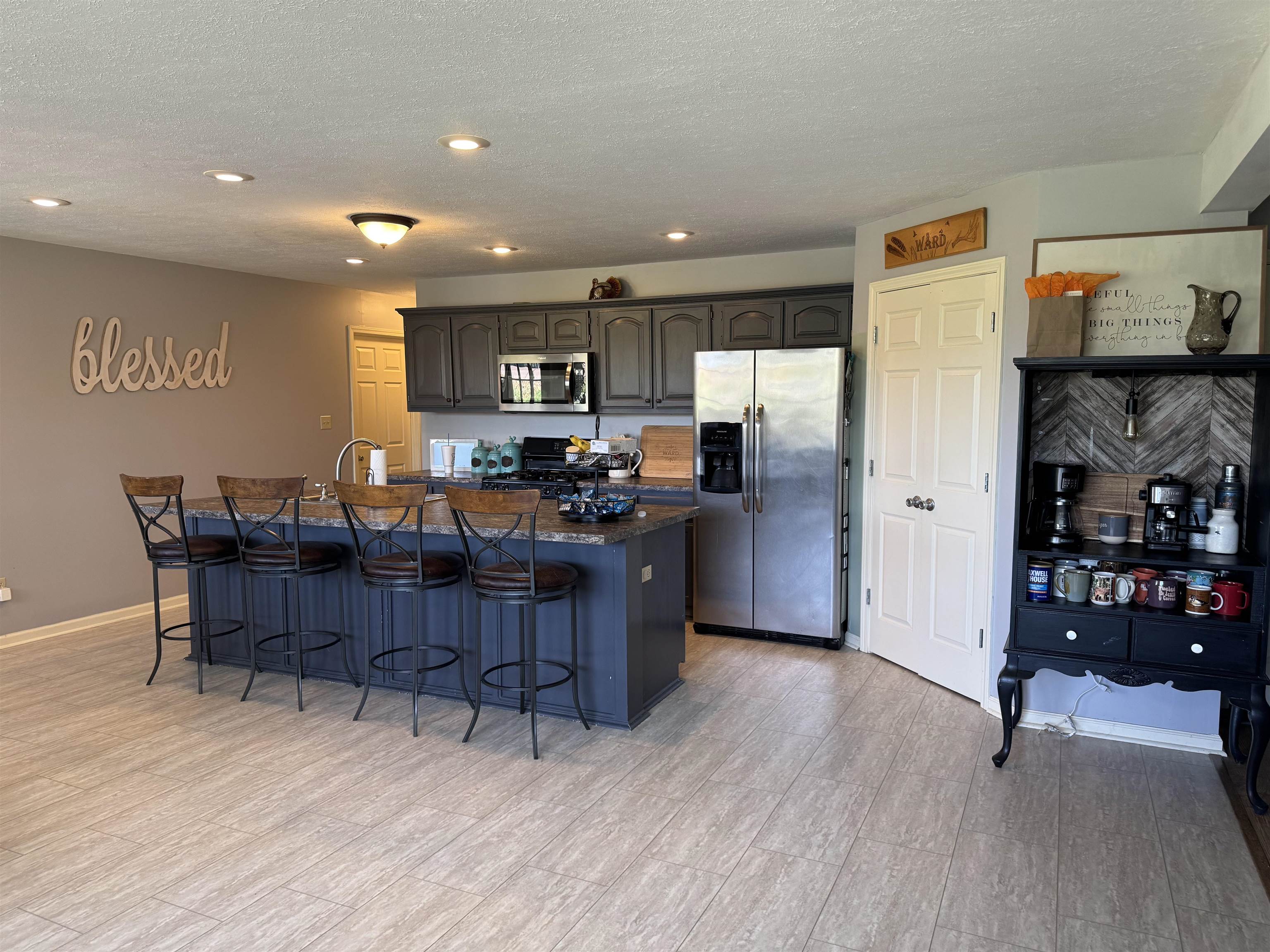 Kitchen featuring an extended island, dark cabinetry, stainless steel appliances, and recessed lighting