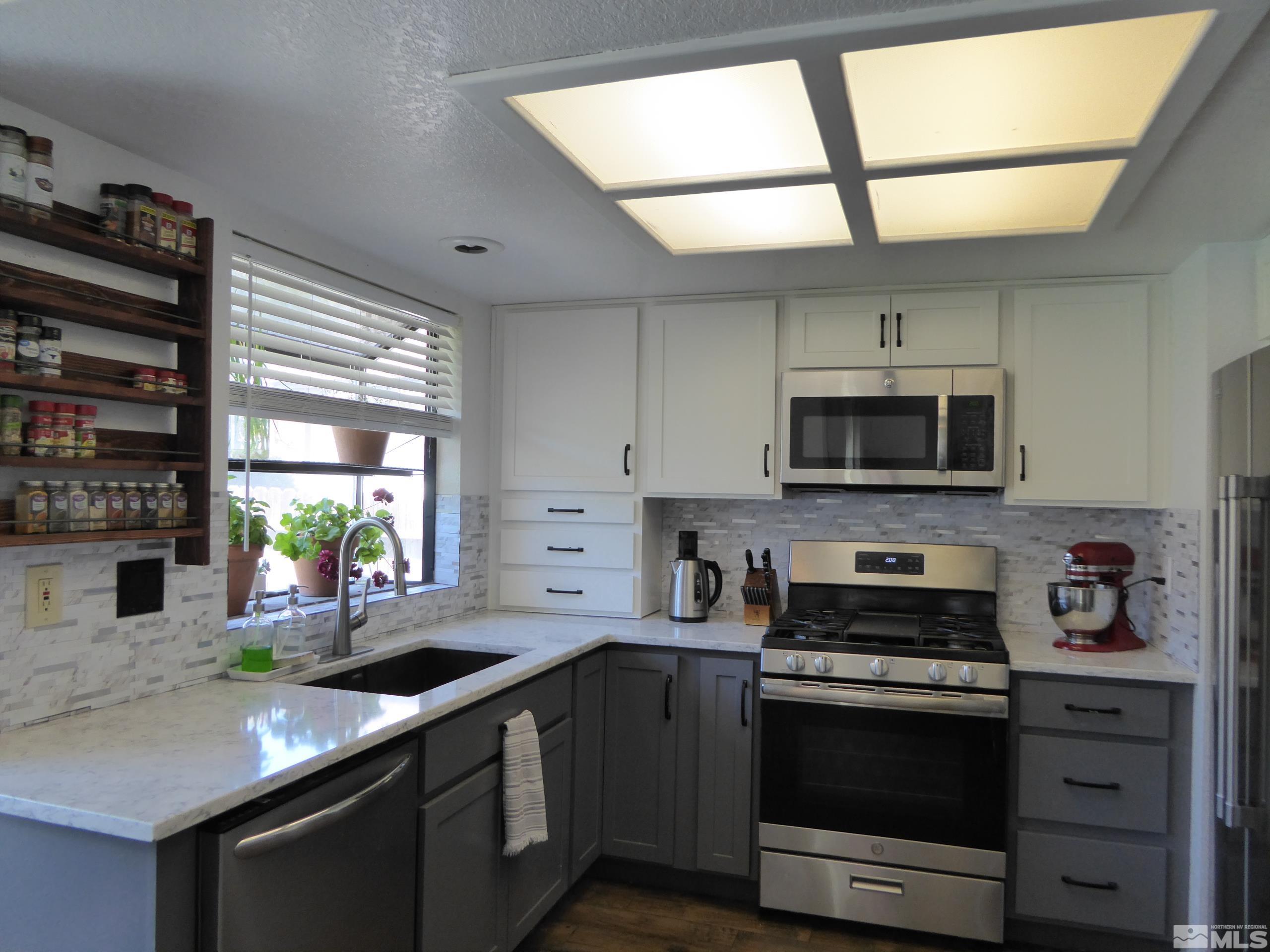 1915 Amarak Way Reno, NV 89523 - Photo 6 of 25 a kitchen with stainless steel appliances granite countertop a sink a stove and a microwave