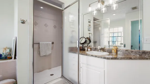 a bathroom with a granite countertop sink a mirror and shower
