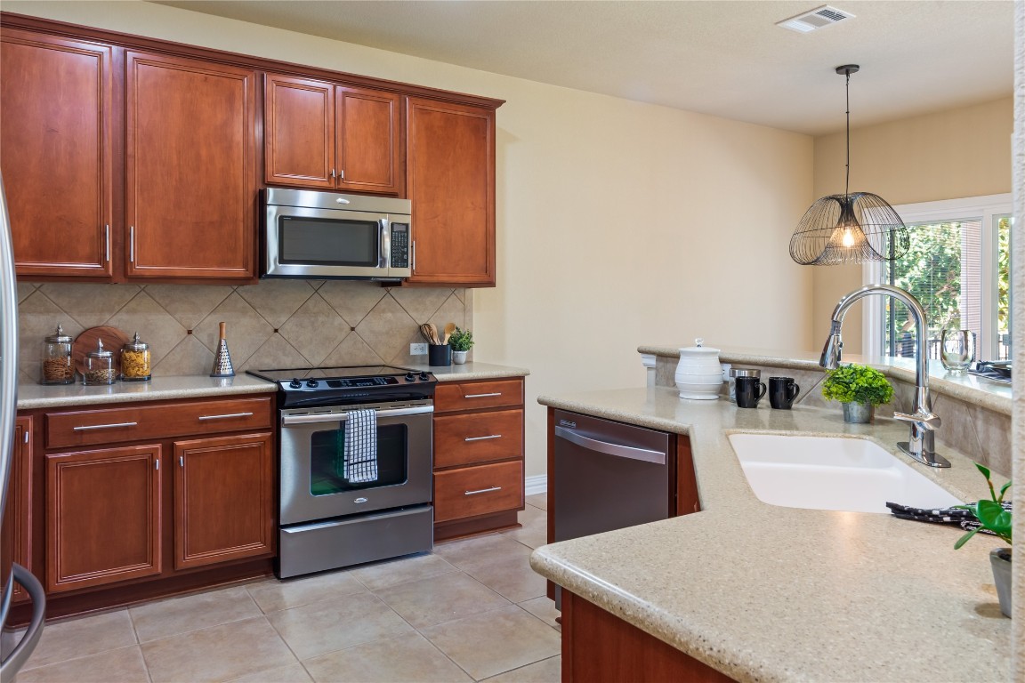 106 Trinity Lane Georgetown, TX 78633 - Photo 9 of 24 a kitchen with stainless steel appliances granite countertop a stove a sink dishwasher and a microwave oven with white cabinets