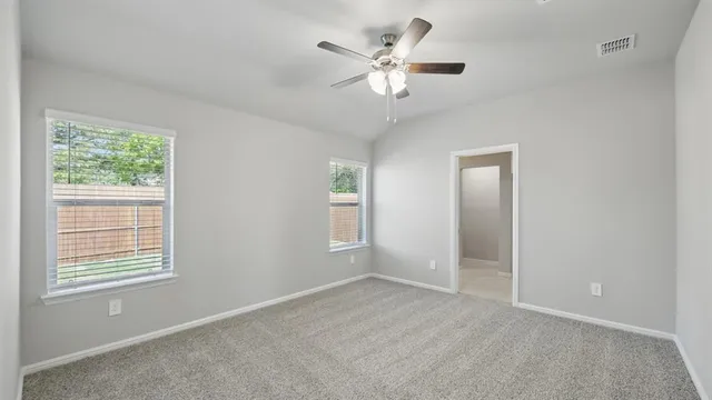 an empty room with wooden floor ceiling fan and window