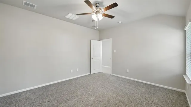 an empty room with windows and fan