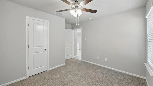 an empty room with a window and a fan