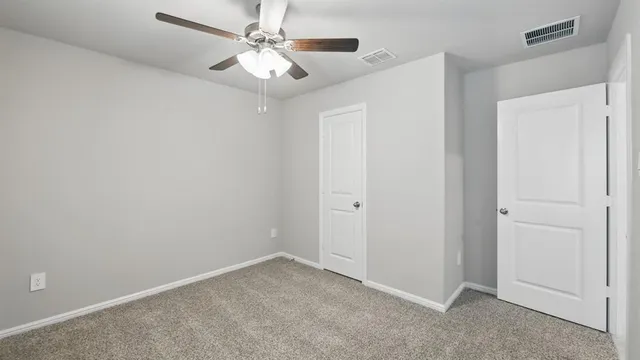 an empty room with a window and chandelier fan
