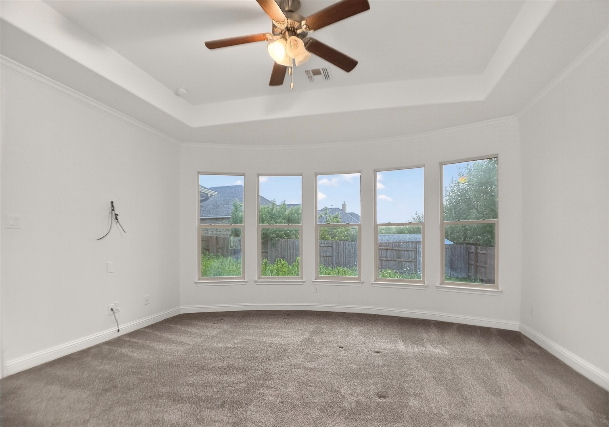 1505 Long Shadow Lane Georgetown, TX 78628 - Photo 13 of 28 Recessed ceiling with crown molding, ceiling fan with light fixture, curved wall with five windows, and wall-to-wall carpeting