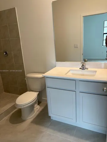 a bathroom with a granite countertop toilet sink and mirror