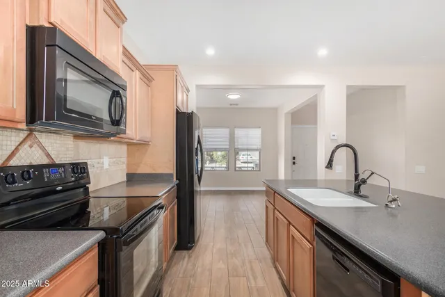 a kitchen with stainless steel appliances granite countertop a sink a stove top oven and wooden floor