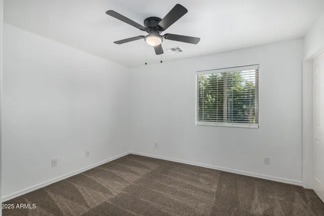 an empty room with a window and a fan
