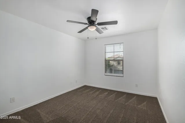 an empty room with a window and a ceiling fan