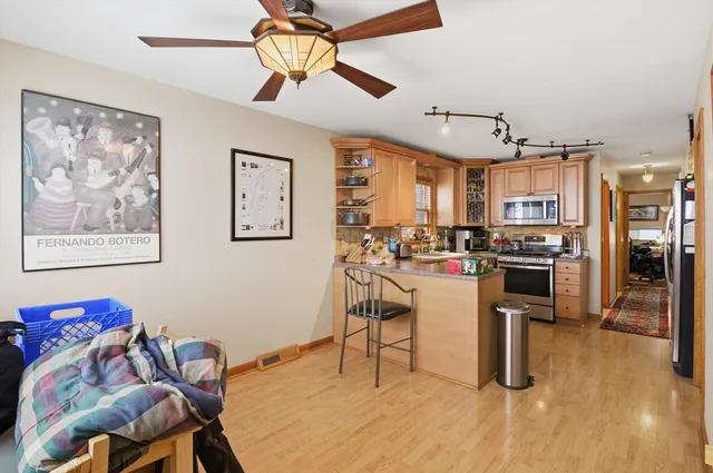 a kitchen with stainless steel appliances granite countertop a refrigerator a stove top oven a sink dishwasher and white cabinets with wooden floor