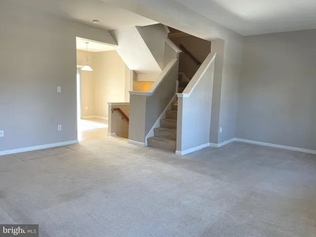 a view of an empty room with stairs and a living room