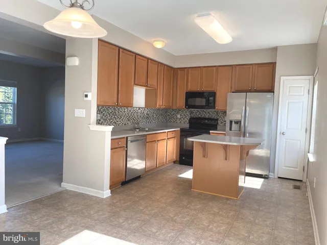 a kitchen with kitchen island granite countertop white cabinets a refrigerator and a stove