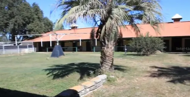 a backyard of a house with table and chairs under an umbrella