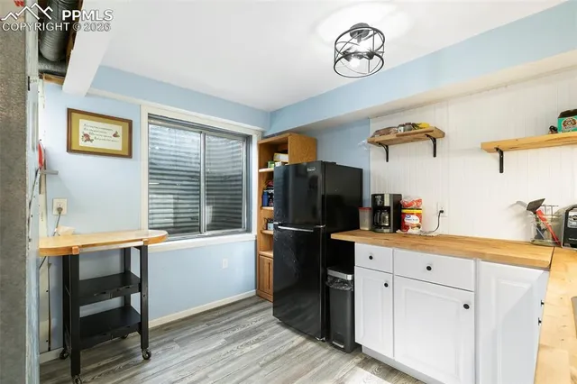 a kitchen with a refrigerator and wooden floor