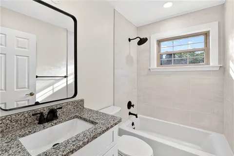 a bathroom with a granite countertop tub sink and mirror