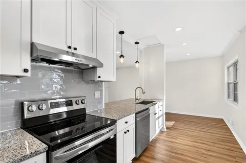 a kitchen with a stove and a wooden floor