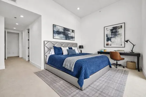 a bedroom with a large bed a workstation with paintings on wall