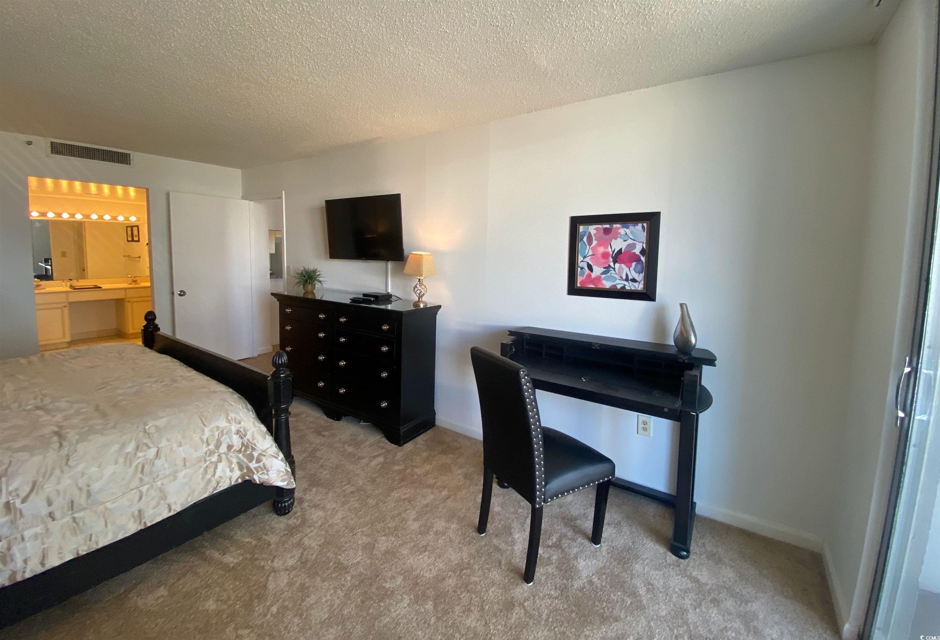 9820 Queensway Boulevard, Unit 206 Myrtle Beach, SC 29572 - Photo 16 of 40 Bedroom with light carpet, ensuite bathroom, and a textured ceiling