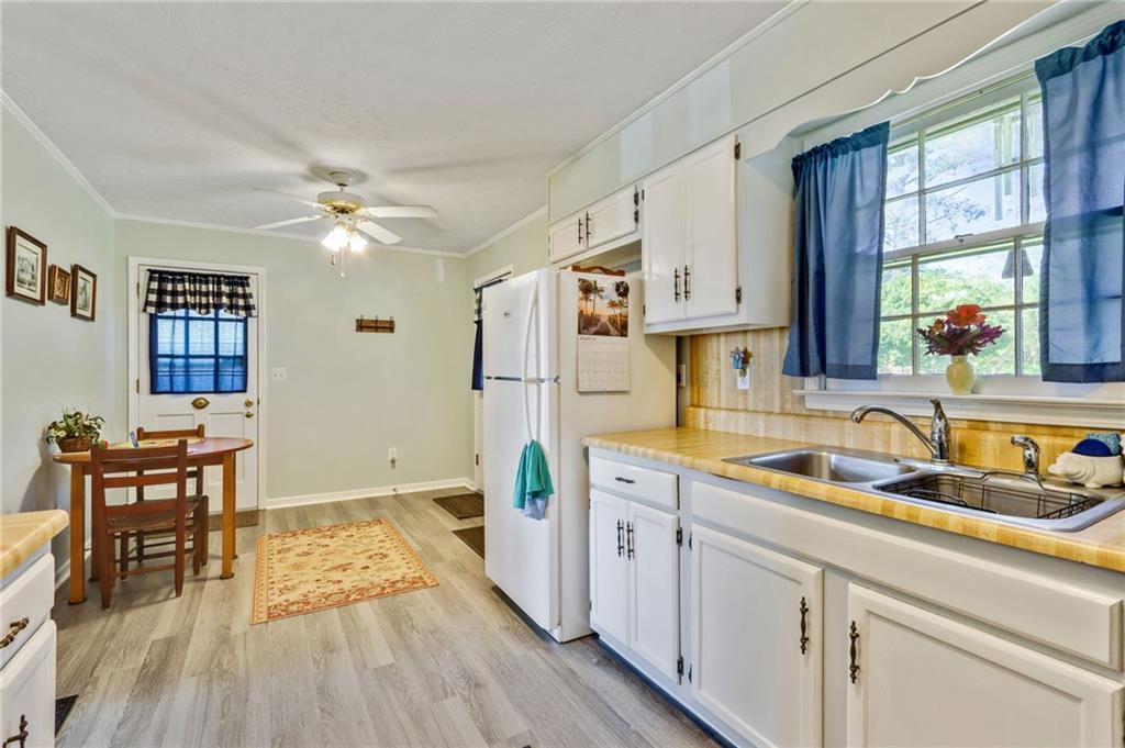 4339 Rex Road Rex, GA 30273 - Photo 3 of 23 a kitchen with a sink dishwasher a stove and white cabinets with wooden floor