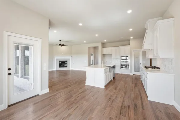 a large kitchen with a large center island wooden floor stainless steel appliances and cabinets