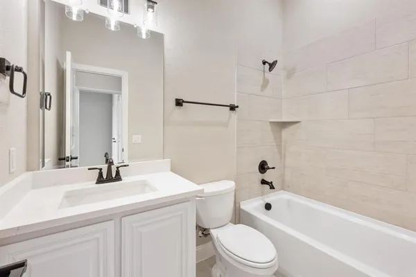 a bathroom with a bathtub shower sink vanity mirror and toilet