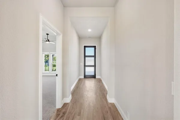 a view of a hallway with wooden floor and a bathroom