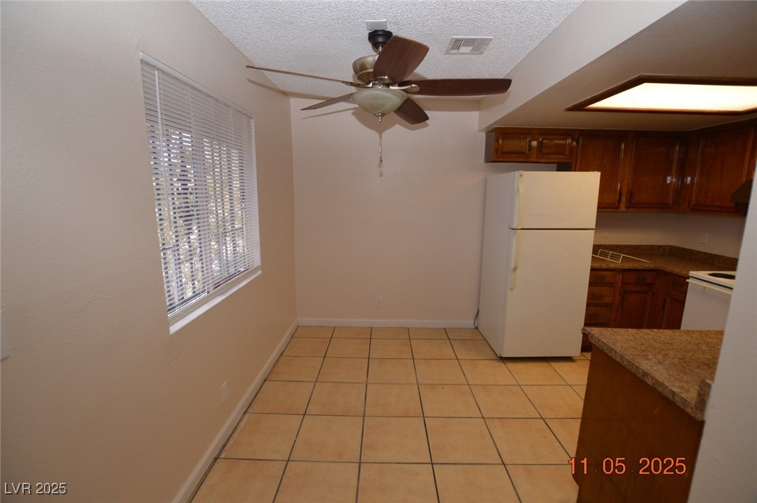 3240 North Mary Dee Avenue, Unit D North Las Vegas, NV 89030 - Photo 4 of 10 Kitchen featuring white appliances, light tile patterned floors, a textured ceiling, a ceiling fan, and dark countertops