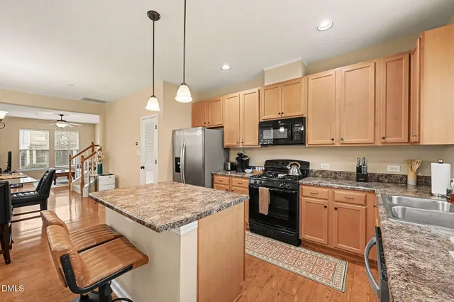 a kitchen with a stove a sink a microwave a refrigerator and chairs