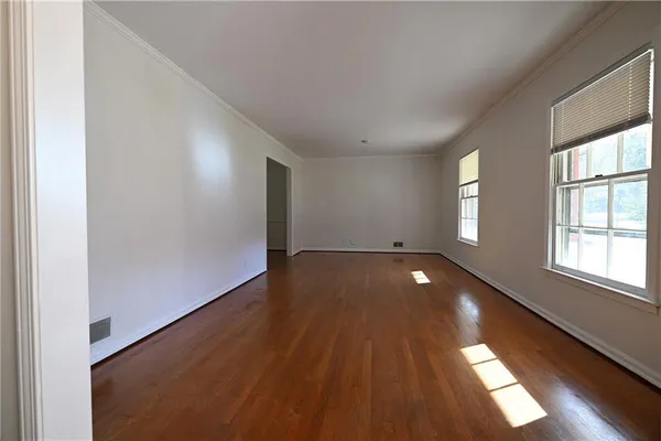 a view of empty room with wooden floor and windows