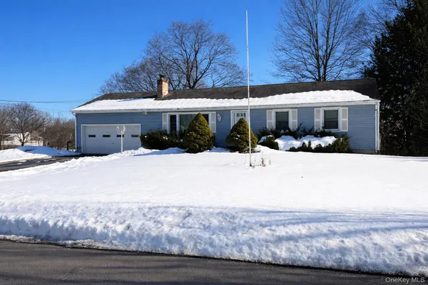 a front view of a house with a yard covered with snow and trees