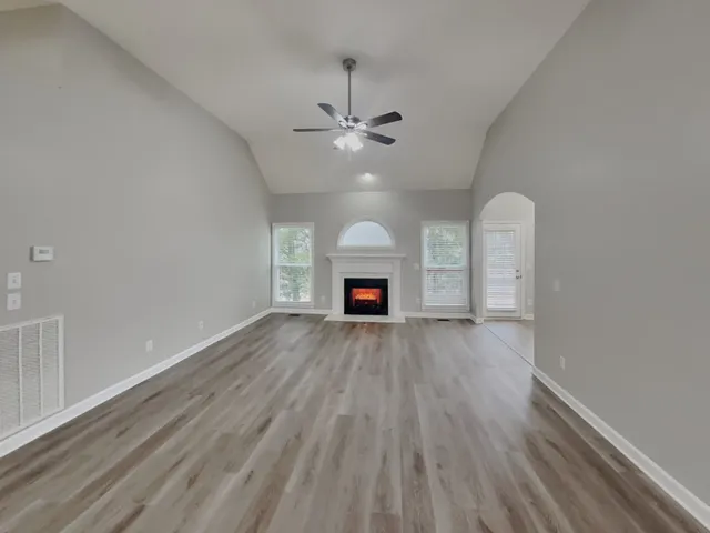 an empty room with wooden floor ceiling fan and window