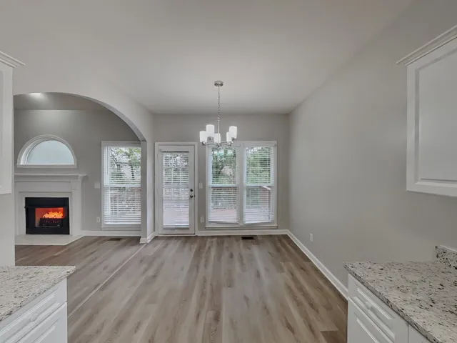 an empty room with wooden floor fireplace and windows